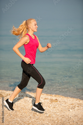 jogging in th beach - woman runns near sea on early summer morning photo