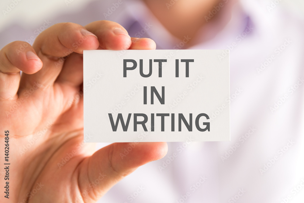 Businessman holding a card with PUT IT IN WRITING message