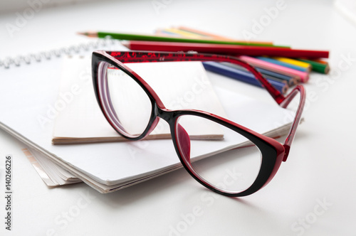Red glasses on the notebook and colored pencils