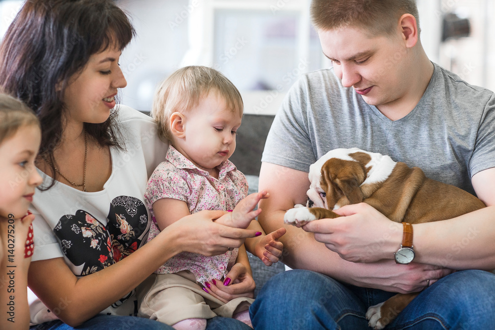 Happy family with puppies of English bulldog on his hands sitting on the couch Happy family with puppies of English bulldog on his hands sitting on the couch
