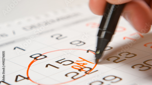 Signing a pay day on a calendar by red pen © Cliplab
