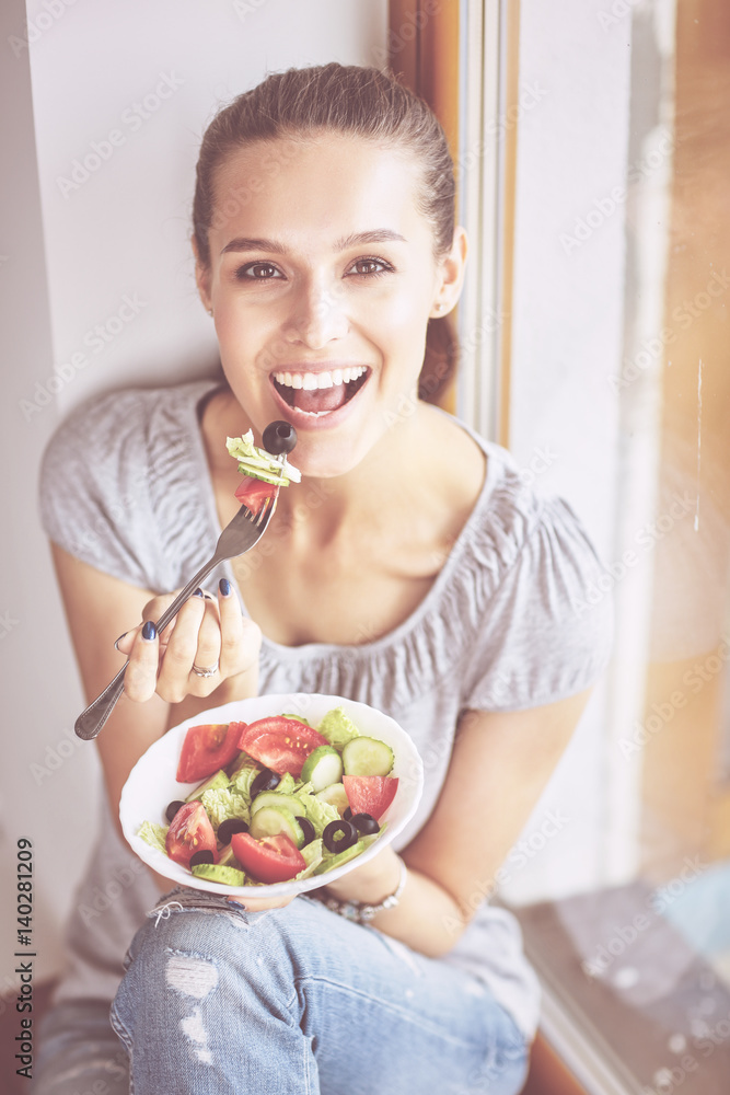 A beautiful girl eating healthy food, sitting near window A beautiful girl eating healthy food, sitting near window