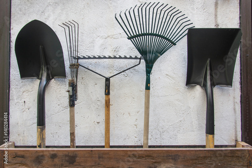 gardening tools, spade, fork and rake on cement wall