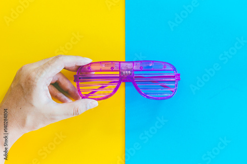Hand holding disco party glasses on colourful background photo