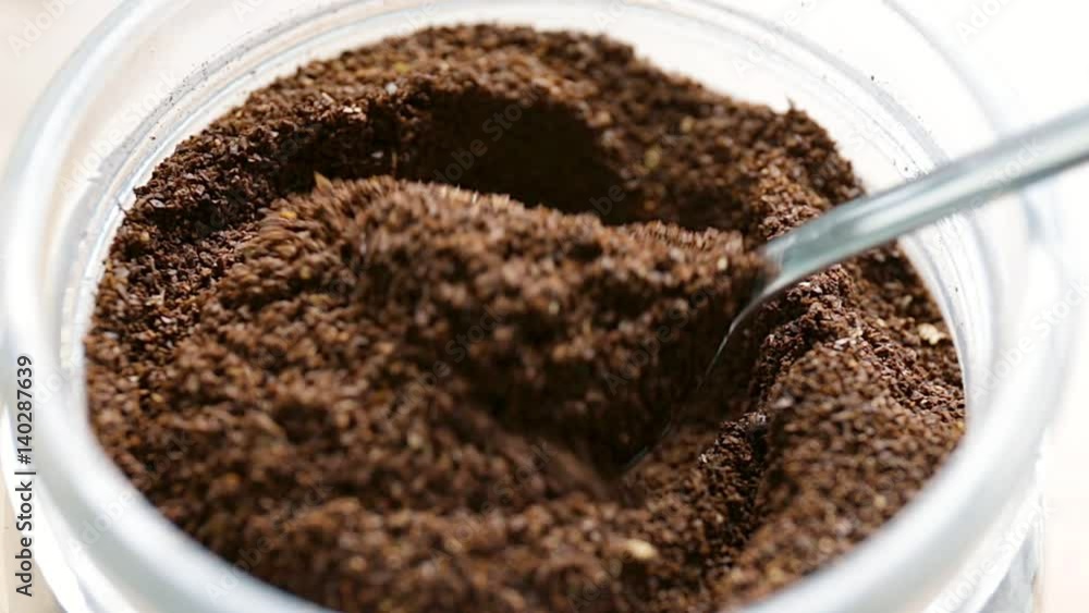 Coffee dosage from a jar with a small spoon on bright white background, macro and close up Coffee dosage from a jar with a small spoon on bright white background, macro and close up