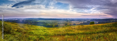 Summer panorama of meadows and forests with a small river and a dramatic sky in Northern Russia.