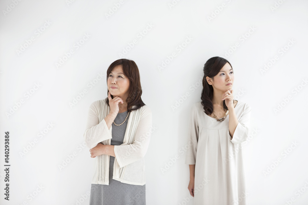 Mother and daughter with finger on chin contemplating Mother and daughter with finger on chin contemplating