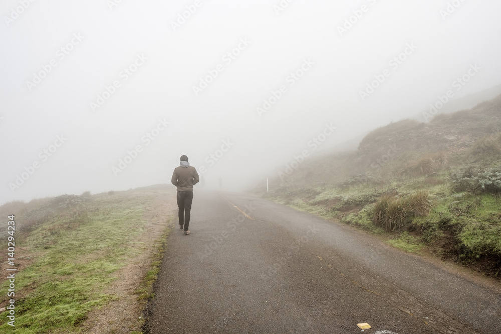 Lone man walking through the white fog
