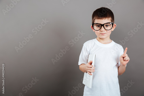 Boy in glasses holding blank magazine and showing thumbs up
