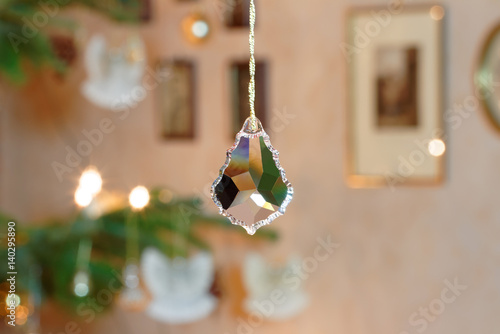 Geschliffener Kristallanhänger vor erleuchteter Weihnachtsbaumkulisse