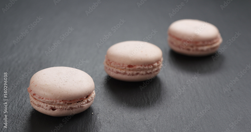 Obraz premium three pink macaroons on slate board, 4k photo