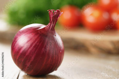 red onion bulb on wood table with copy space, shallow focus