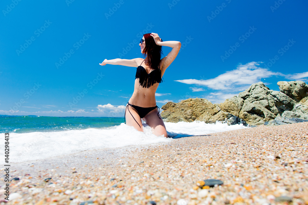 beautiful young woman sitting on the wonderful sand beach in greece