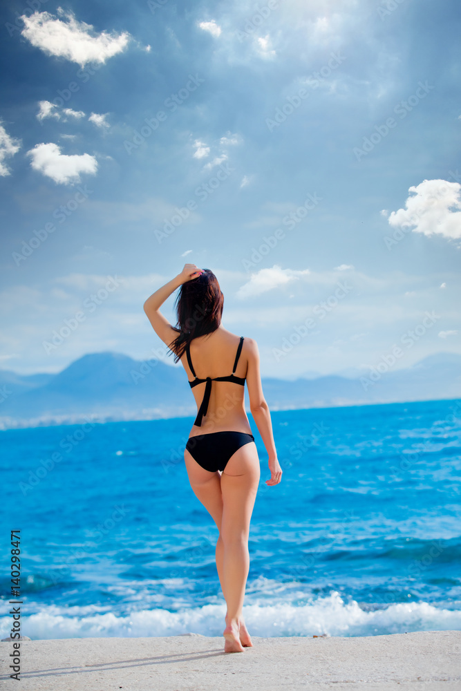 beautiful young woman standing in front of wonderful sea background in Greece
