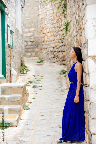 photo of beautiful young woman standing near the wall on the street in Greece © Masson