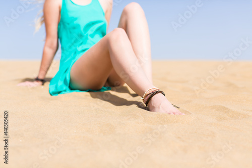 Girl with bare legs in a blue dress in a sandy desert