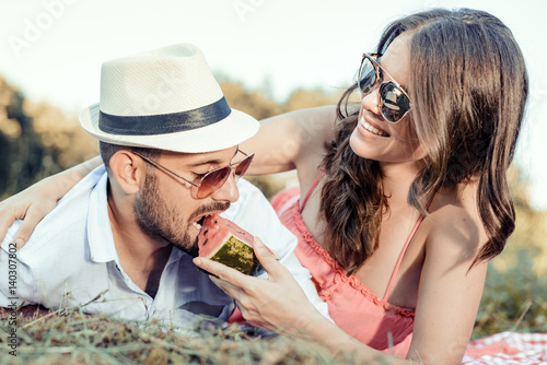 Young couple eating watermelon on a picnic date