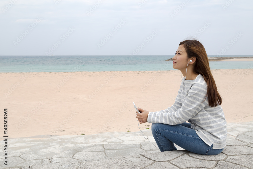 海岸で音楽を聴く若い女性