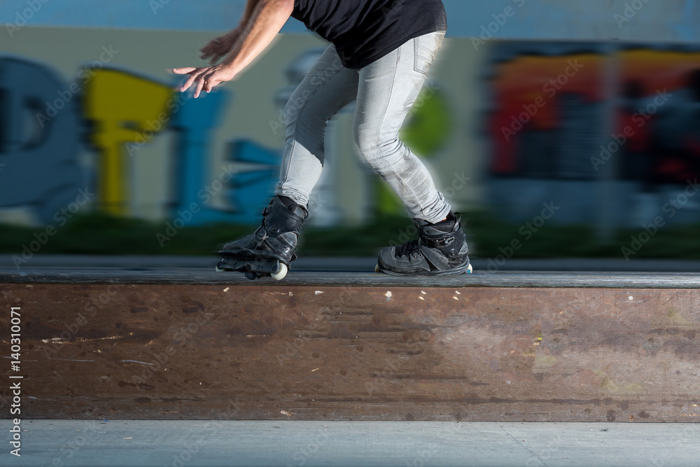 Young man rollerblading. Rollerblader near graffiti. Not afraid of speed. Legs of person on inline skates close up. driving concept on rollers on a stage.
