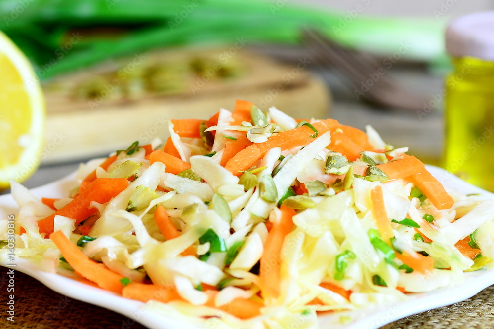 Delicious vegetable salad on a plate. Homemade salad with white cabbage, carrots, green onions, pumpkin seeds, lemon juice and olive oil. Easy diet food. Closeup Delicious vegetable salad on a plate. Homemade salad with white cabbage, carrots, green onions, pumpkin seeds, lemon juice and olive oil. Easy diet food. Closeup