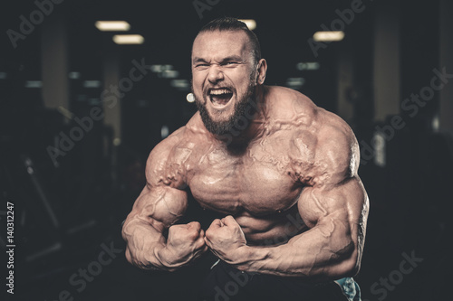 Handsome fit caucasian muscular man flexing his muscles in gym © antondotsenko