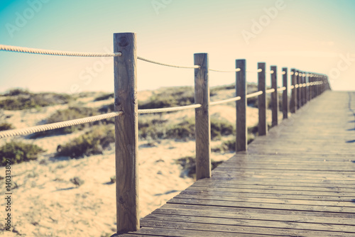 Wooden bridge path with sand dunes landscape over sunny sky outdoors background © aquar