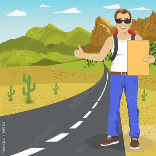 Hitchhiking man with backpack and sunglasses holding cardboard standing on highway. Adventure and tourism concept.