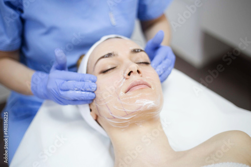 Beautiful woman at spa salon, Cosmetician woman applying facial mask.