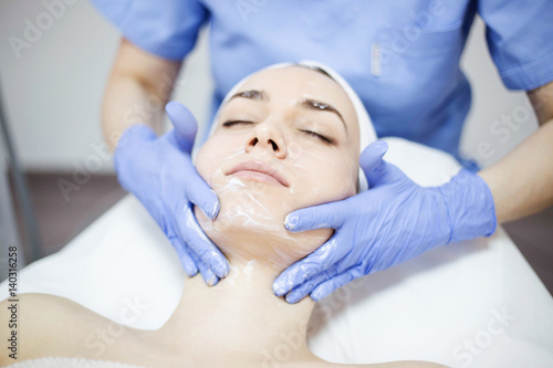 Beautiful woman at spa salon, Cosmetician woman applying facial mask.