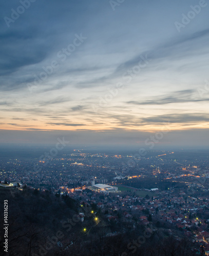 View from the hill on a city in the valley at sunset