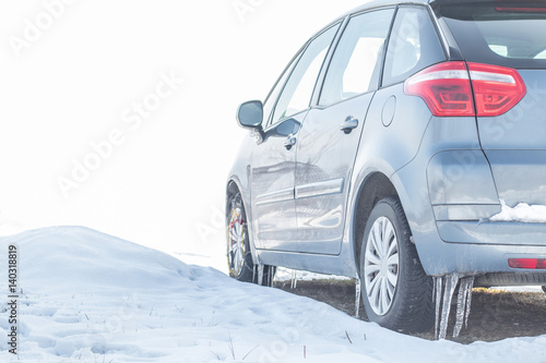 Huge icicles on the dirty car wheel. Dangerous ice build up car wheel fender arch. Driving problems. Extreme winter series. Frozen car wheel in ice and snow. Close up of car tire on the snowy road.