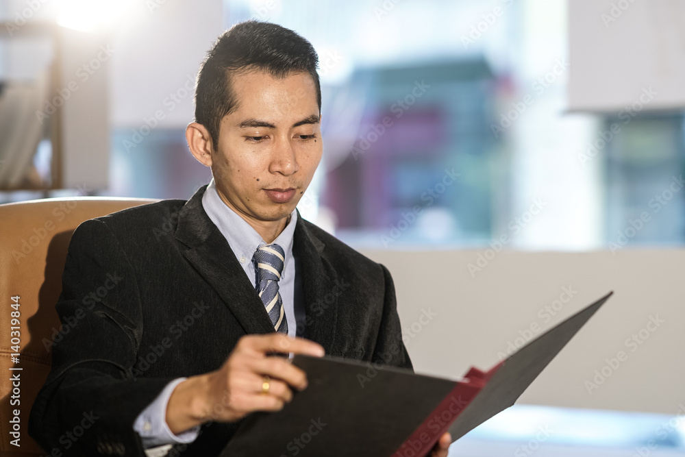 Fototapeta premium Thai white collar worker posing at desk in office reading documents