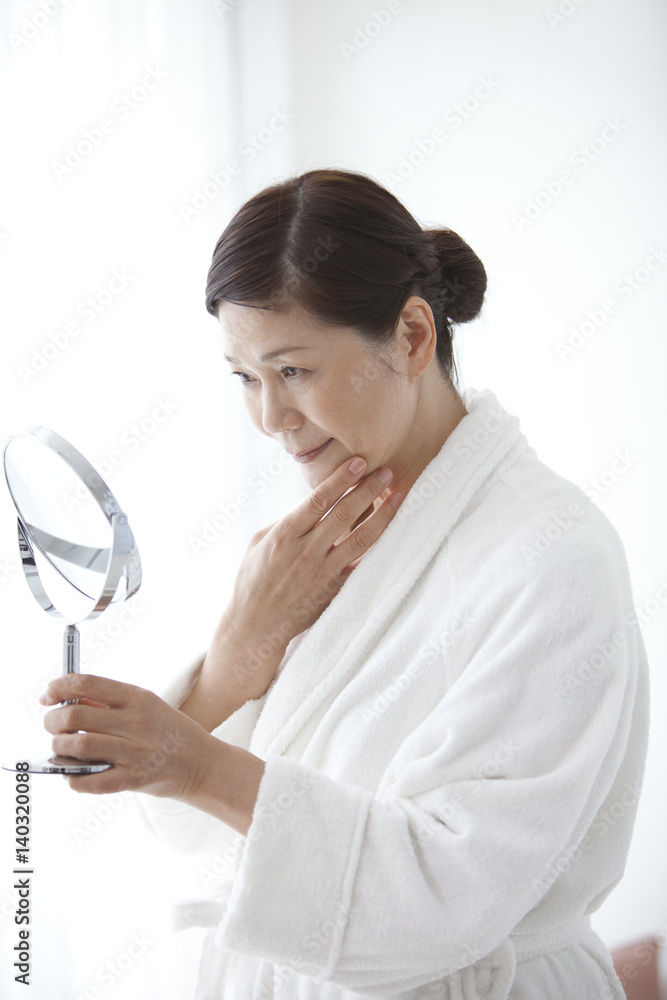 Middle-Aged Woman Wearing Bathrobe Looking Into Mirror Middle-Aged Woman Wearing Bathrobe Looking Into Mirror