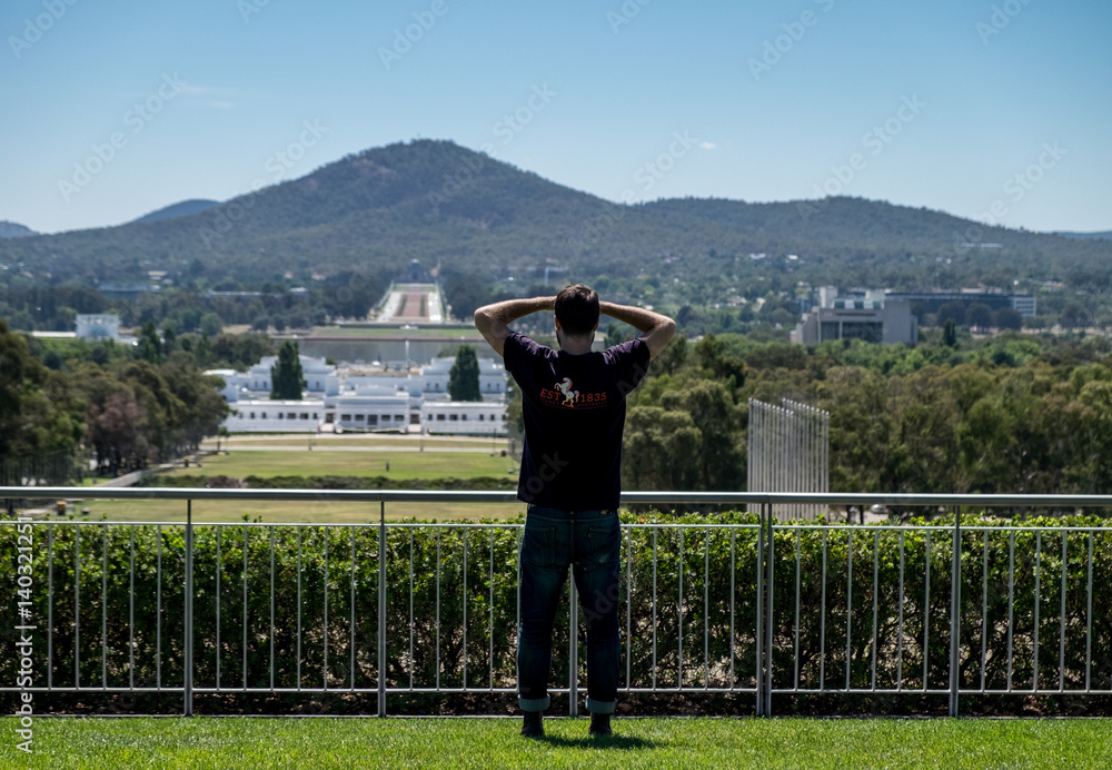 Man looking out at city landscape with hands on head Man looking out at city landscape with hands on head
