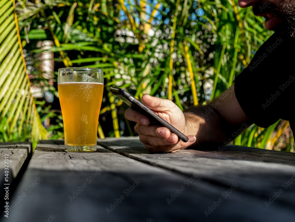 Young man checking his phone whilst sitting in beer garden Young man checking his phone whilst sitting in beer garden