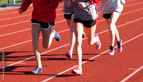 Four girls training together on a red track in spikes