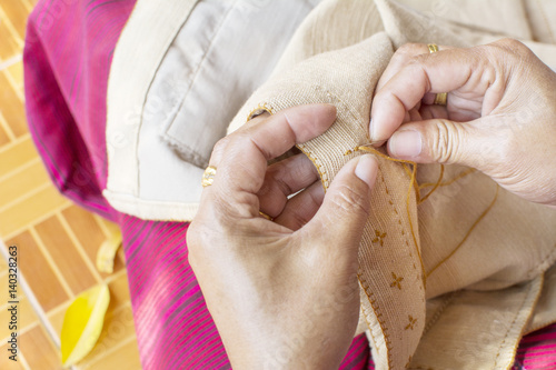 old woman's hand to picth brown yarn in to clothes by needle photo