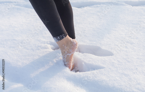 Girl barefoot on white cold snow in winter. Quenching tempering harding health concept. Female feet without shoes.