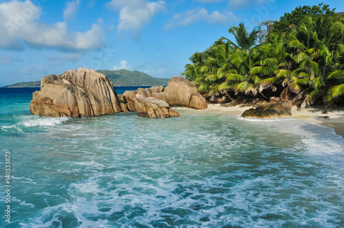 Granite stones on tropical white-sand beach next to turquoise water © chalik