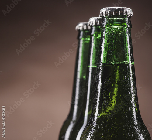 Glass bottles of beer on brown background