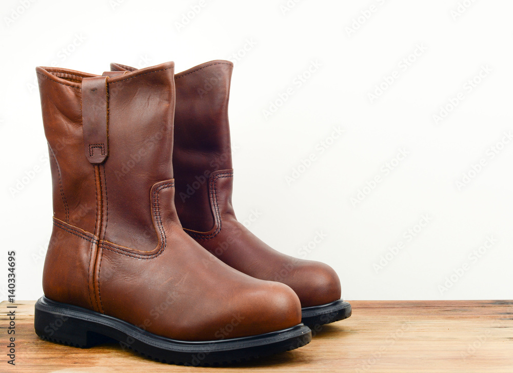 A pair of brown color leather safety boot with white background