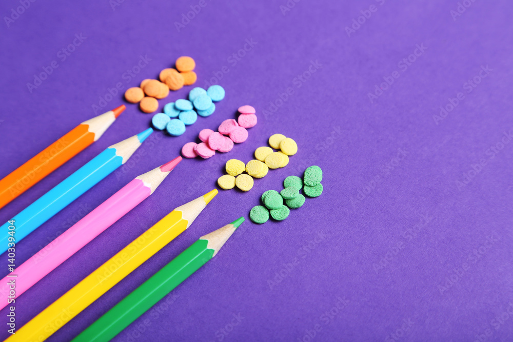 Colorful sprinkles with pencils on the purple background Colorful sprinkles with pencils on the purple background