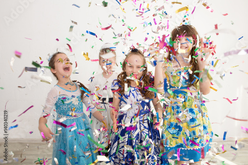 Happy children having fun celebrating birthday. Group of children throws up multi-colored tinsel and confetti. Positive emotions.