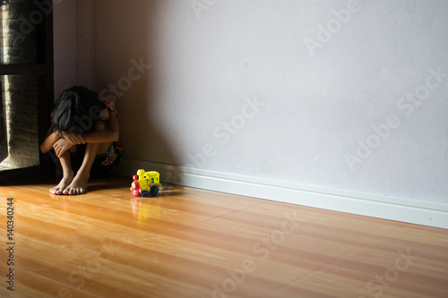 sad children,girl sitting alone in corner at home