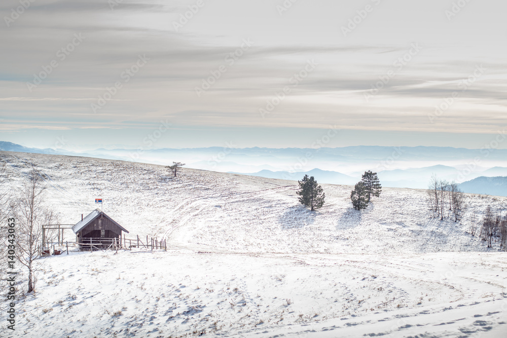 Old lonely wooden small hunting house cabin on top of serbian mountains in winter in winter landscape.