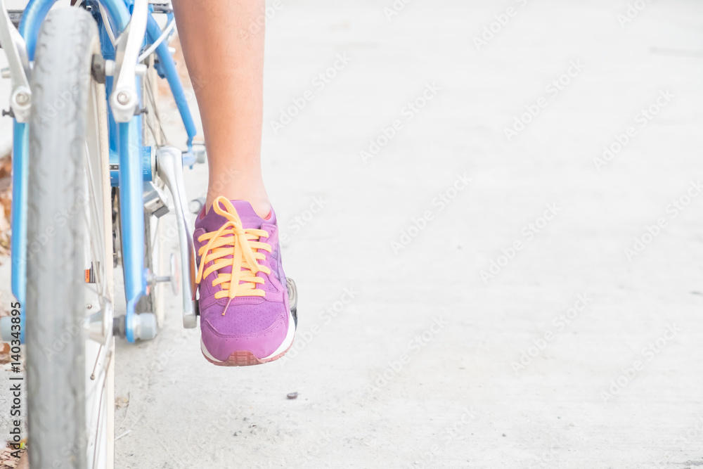 shin of woman and purple shoes on blue bicycle with empty copy space for background.