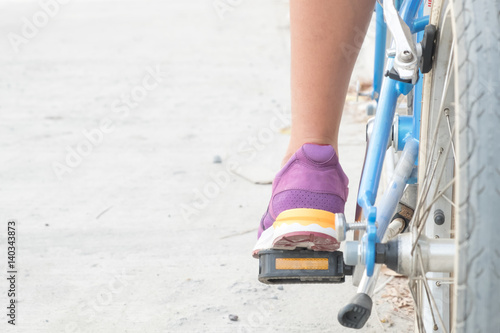 calf of woman and purple shoes on blue bicycle with empty copy space for background.