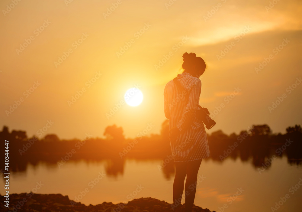 Woman holding a camera in  sunset