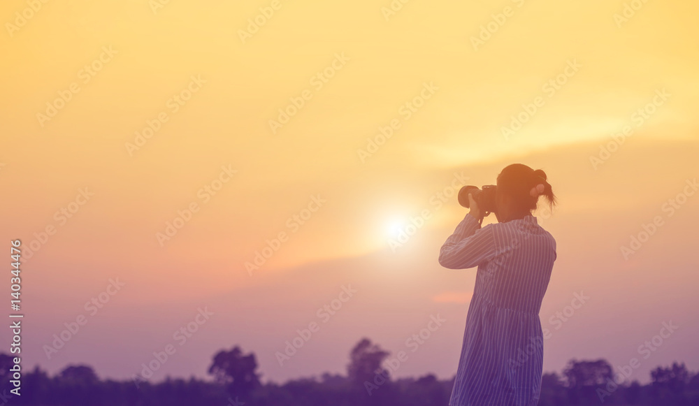 Woman holding a camera in  sunsets 