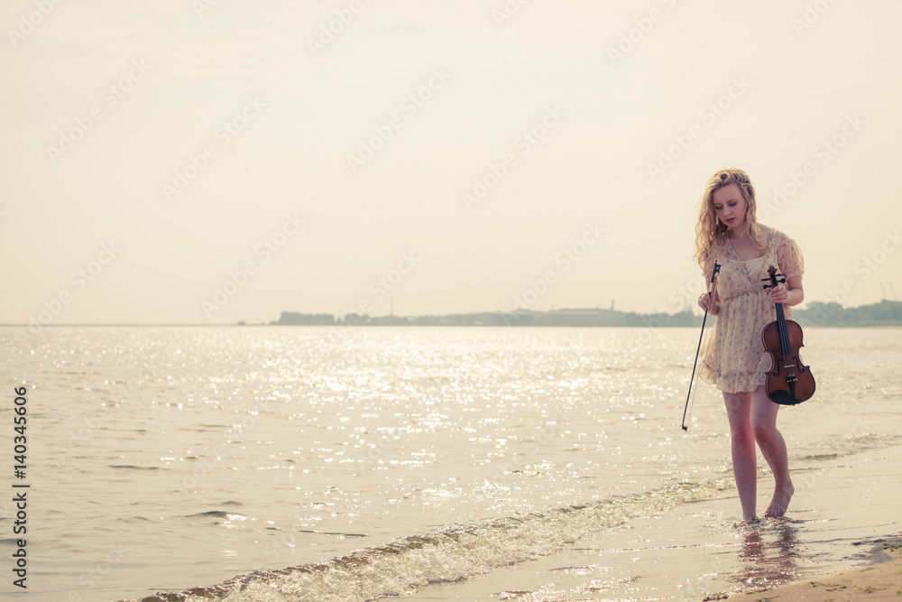 Woman on beach near sea holding violin Woman on beach near sea holding violin